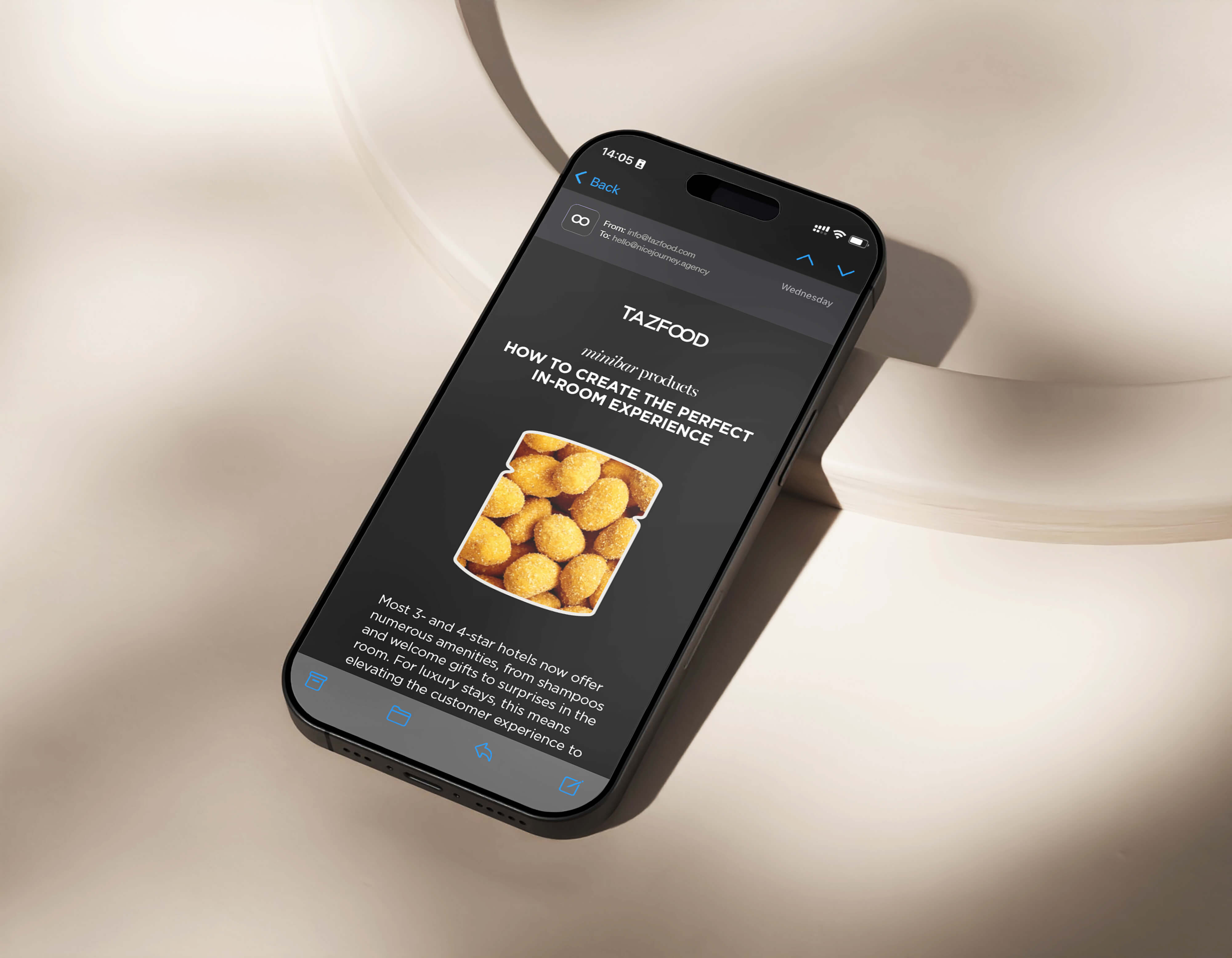 Smartphone displaying an email from TAZFOOD about minibar products titled 'How to create the perfect in-room experience' with an image of golden coated snacks and partial text about 3- and 4-star hotels offering amenities and welcome gifts.