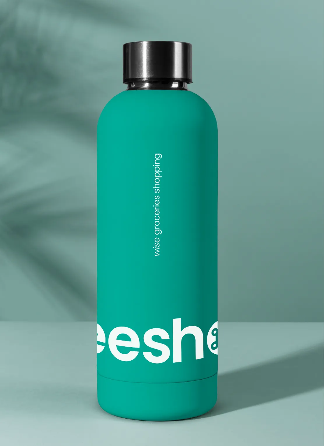 Teal reusable water bottle with a black cap, featuring partial white text and a vertical slogan that reads 'wise groceries shopping' on a teal background with shadowed palm leaves.